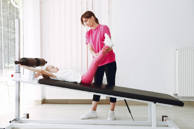 Mother with little daughter are engaged in gymnastics in the gym