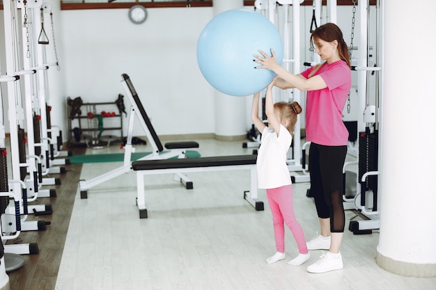 Mother with little daughter are engaged in gymnastics in the gym