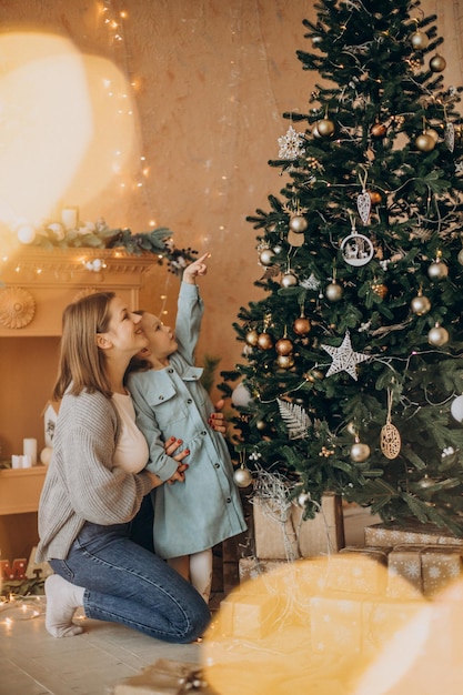 Mother with little daughter decorating christmas tree with toys