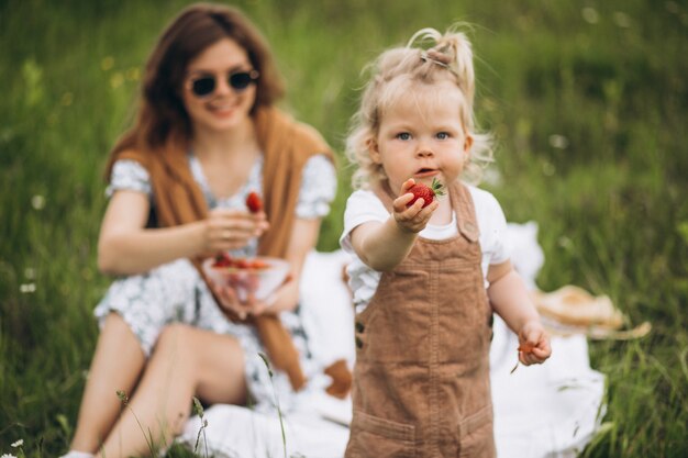 Mother with little daughter having picnic in park