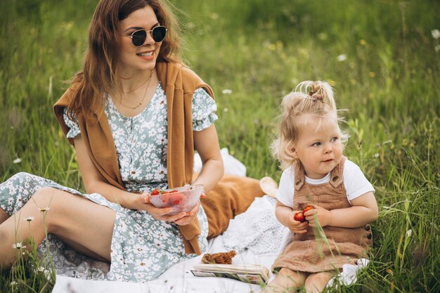 Mother with little daughter having picnic in park