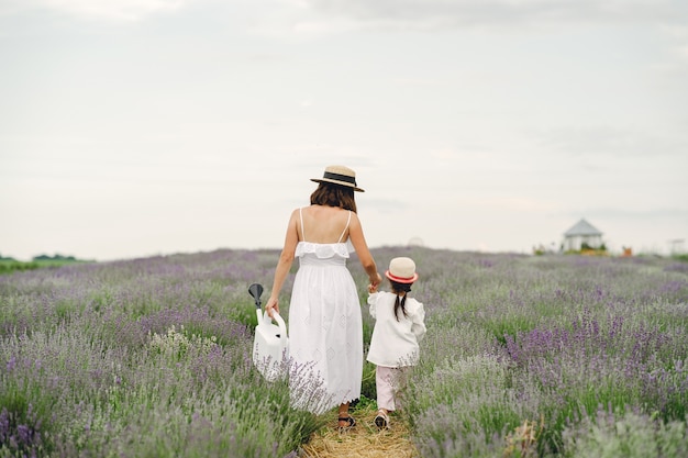 Free photo mother with little daughter on lavender field. beautiful woman and cute baby playing in meadow field. family holiday in summer day.