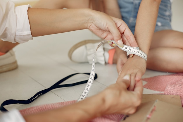 Mother with little daughter measure the fabric for sewing