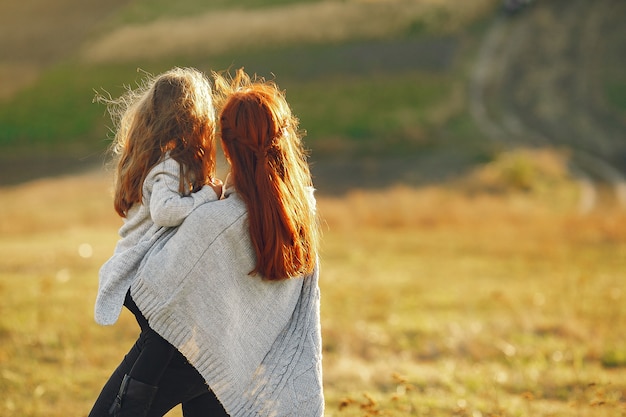 Mother with little daughter playing in a autumn field