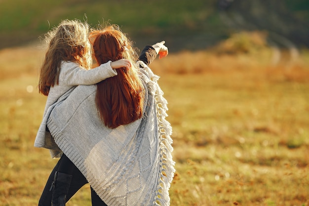 Mother with little daughter playing in a autumn field