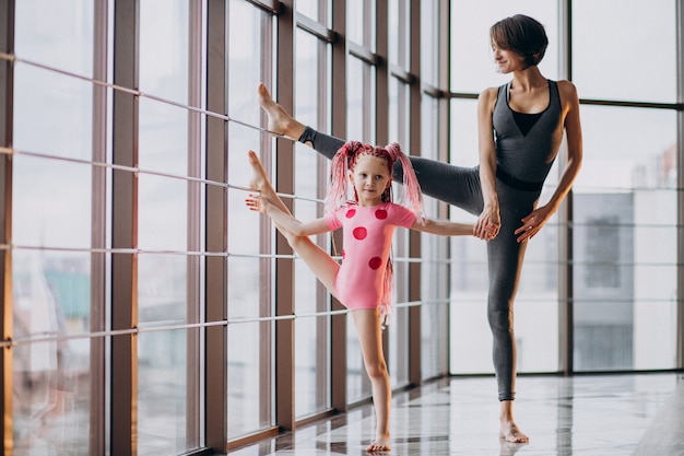 Mother with little daughter practicing yoga by the window