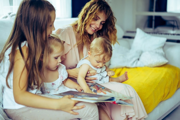 mother with three children reading a book in a homely atmosphere