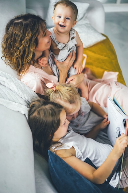 mother with three children reading a book in a homely atmosphere