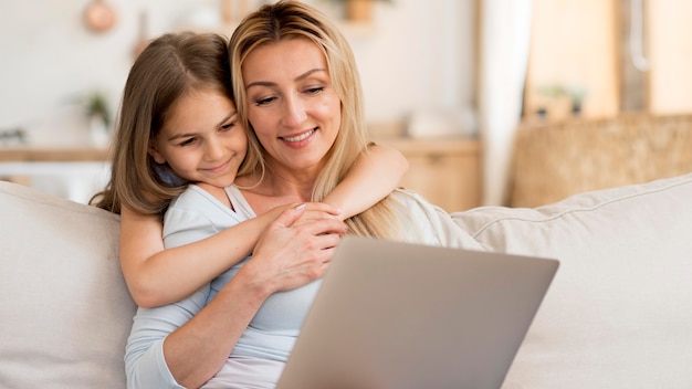 Free photo mother working on laptop from home with daughter embracing her