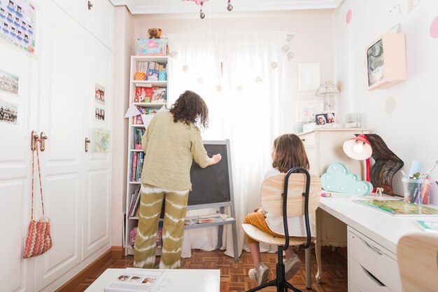 Mother writing on chalkboard for daughter