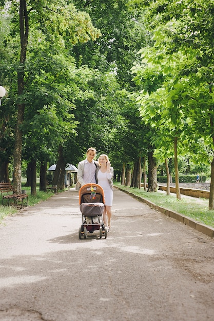 Mother and young father walking their baby in the park