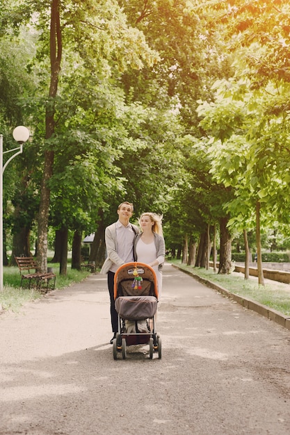 Free photo mother and young father walking their baby in the park