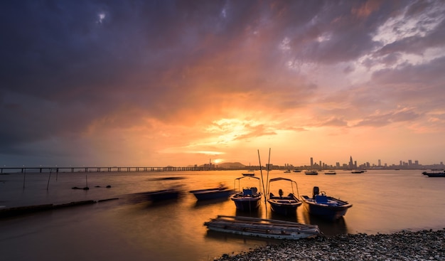 Motorboats parked on the water by the water with sunset and a city visible