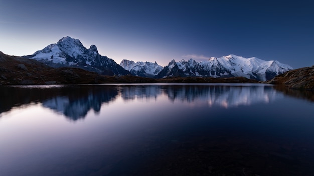 Free photo mount mont blanc covered in the snow reflecting on the water in the evening in chamonix, france