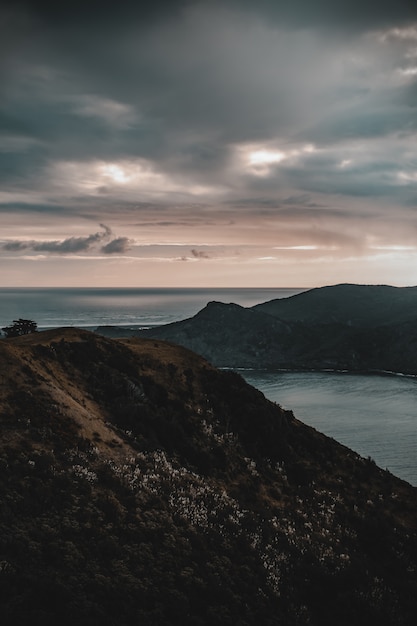 Mountains near water under a cloudy sky