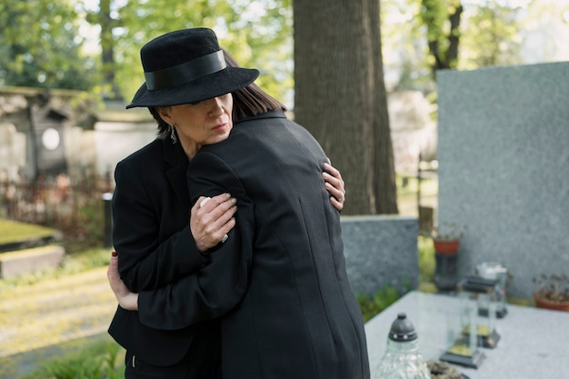 Free Photo mourning mother and daughter at a grave in the cemetery