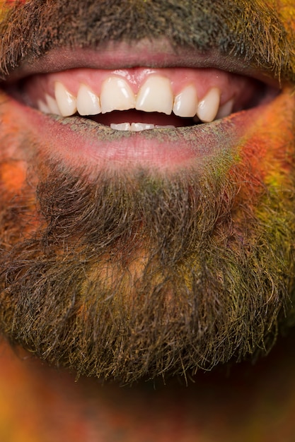 Free photo mouth of toothy smiling bearded man with rainbow paint on face