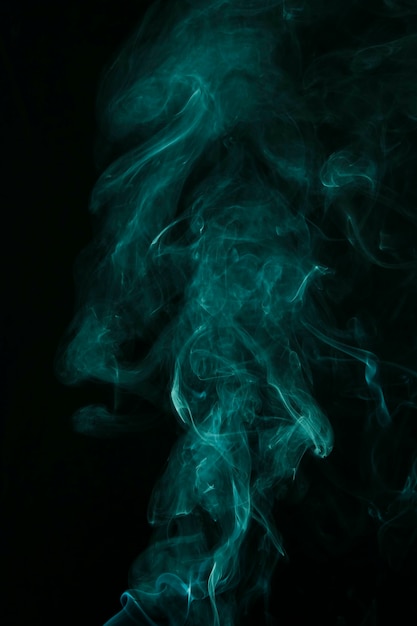 Movement of turquoise smoke spread on black background