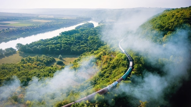 Free photo moving train on railway with high column of smoke, flowing river, hills and railway on the foreground