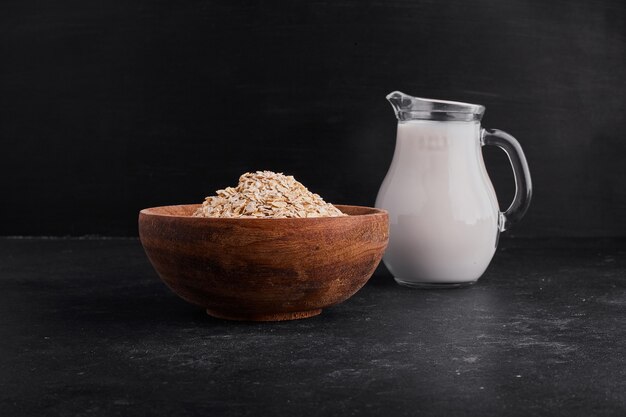 Muesli in a wooden bowl served with a jar of milk. 