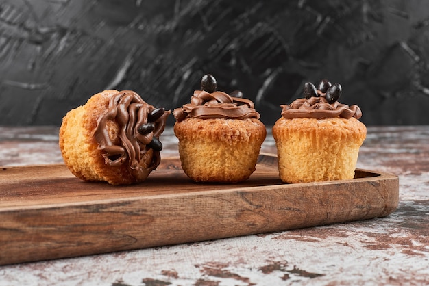 Muffins with cocoa cream on a wooden board.