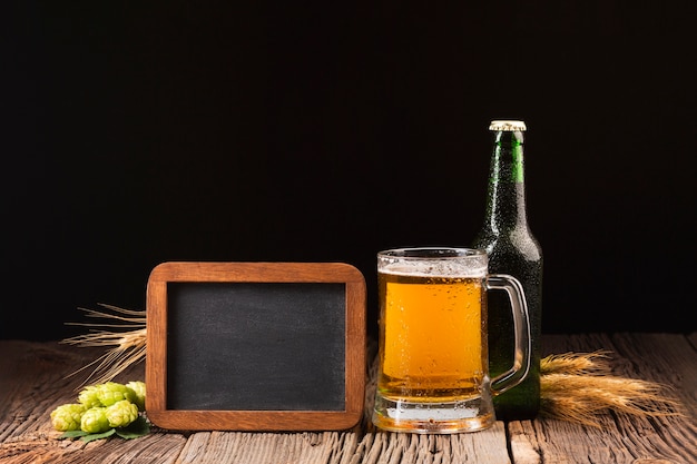 Free Photo mug and bottle of beer on wooden background