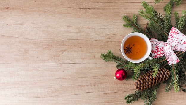 Mug of drink near coniferous twigs and snags