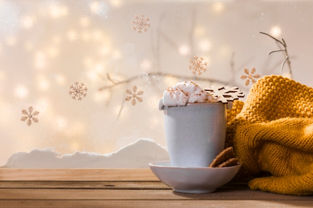 Free Photo mug on plate with cookies near scarf on wood table near bank of snow and fairy lights