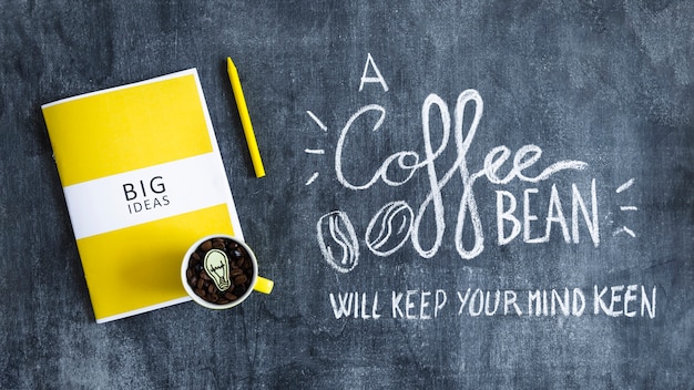 Free Photo mug with coffee beans with light bulb over the big ideas book and text on blackboard