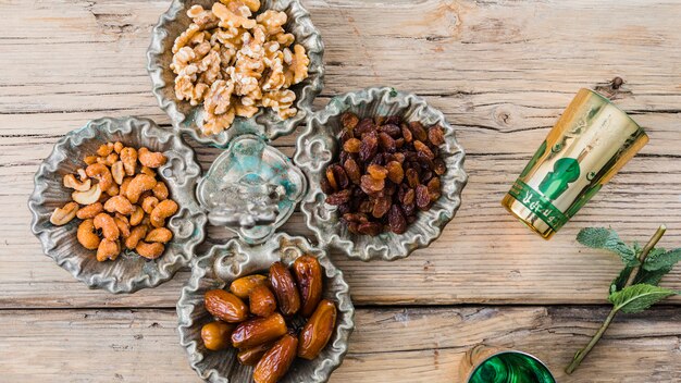 Mugs near plant twig, dried fruits and nuts on board