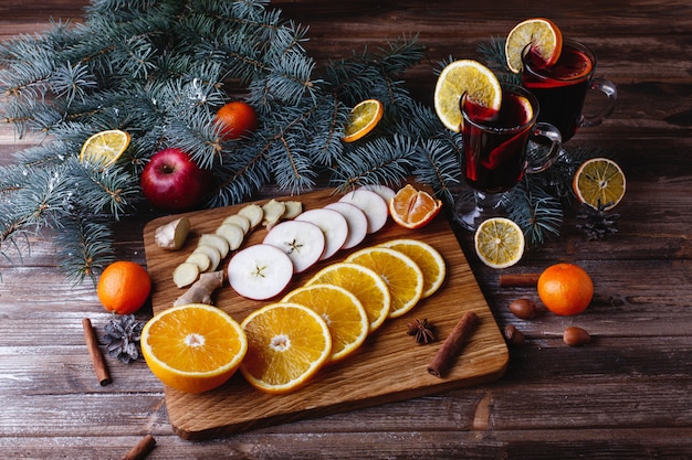 Mulled wine cooking. Oranges, apples and species lie on wooden table 