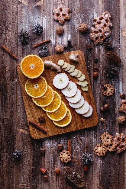 Mulled wine cooking. Oranges, apples and species lie on wooden table 