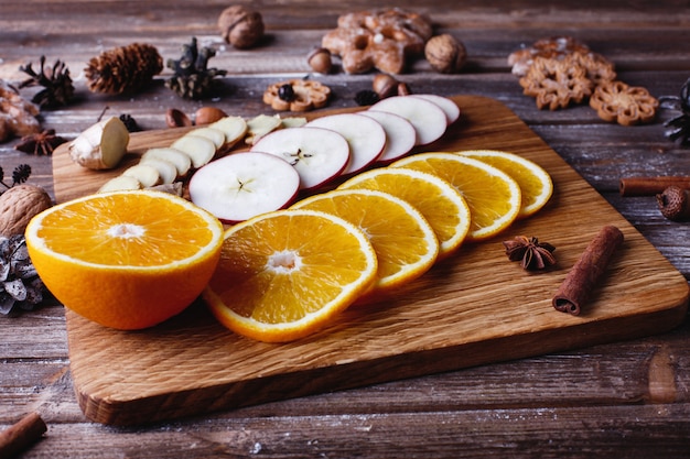 Mulled wine cooking. Oranges, apples and species lie on wooden table 