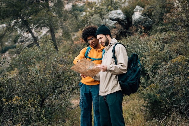 Multi ethnic male hiker looking at map in the forest