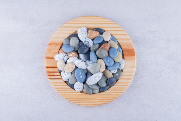 Multicolor beach stones in a platter on concrete surface