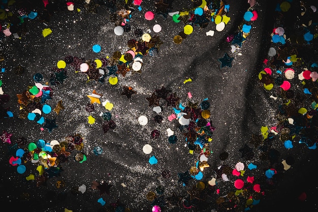 Free photo multicolored confetti on dark textile