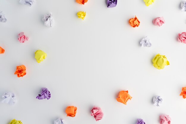 Multicolored crumpled paper arranged in circular frame on white backdrop