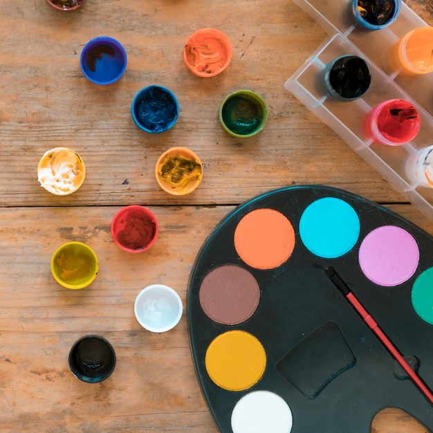 Free photo multicolored gouache and palette with paint brush