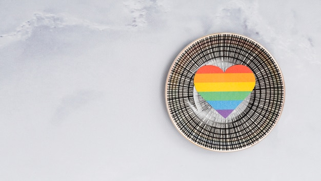 Free photo multicolored lgbt heart on round plate on white background