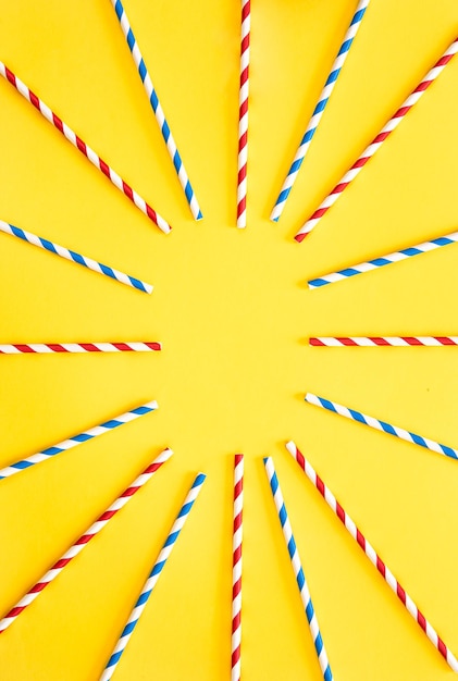 Free photo multicolored party drinking straws arranged into a circle on yellow background