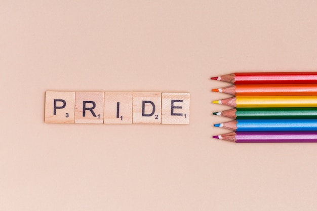 Free Photo multicolored pencils and pride text on beige background