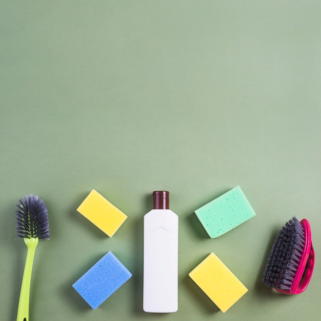 Free Photo multicolored sponge with bottle and brush on green backdrop