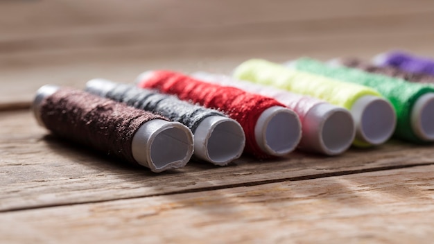 Free photo multicolored thread reels on wooden surface