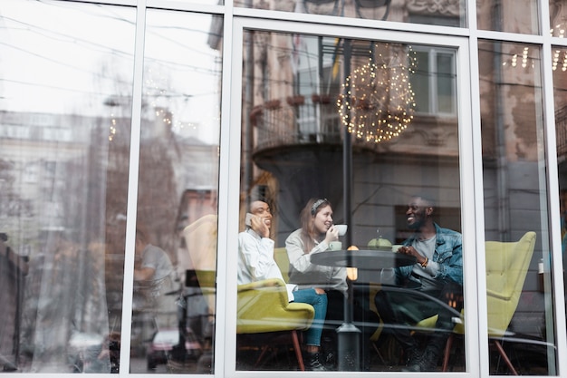 Free photo multicultural friends sitting near window