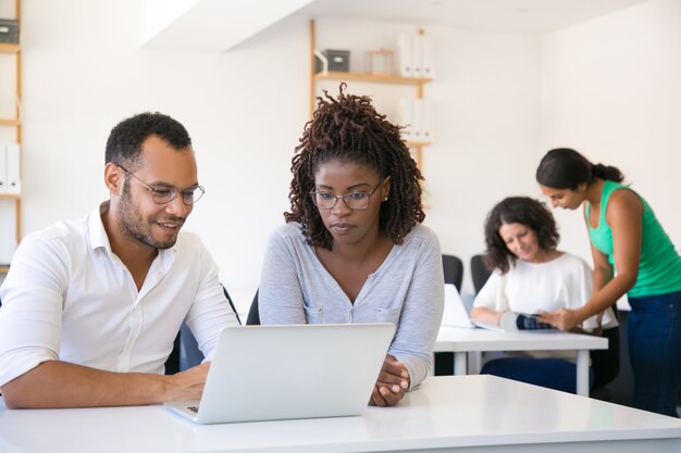 Free photo multiethnic colleagues looking at laptop screen