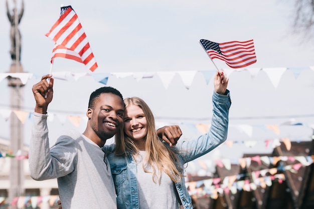 Free photo multiethnic friends holding american flags in outstretched hands