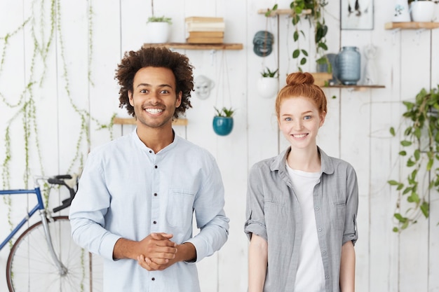 Free Photo multiethnic team of two coworkers standing in cozy office interior