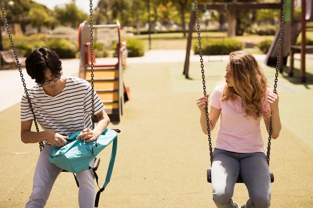 Multiethnic teenagers sitting on swings