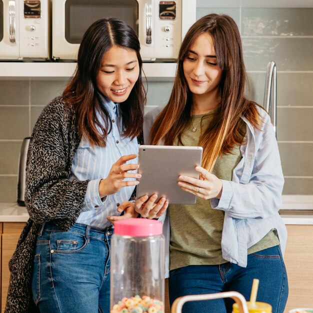 Multiethnic women with tablet on kitchen