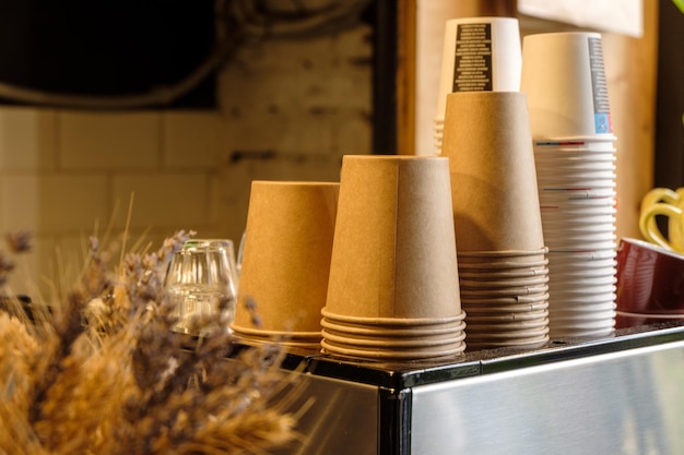 Free Photo multiple reusable paper cups in a local coffee shop on a coffee machine near some ornamental flowers